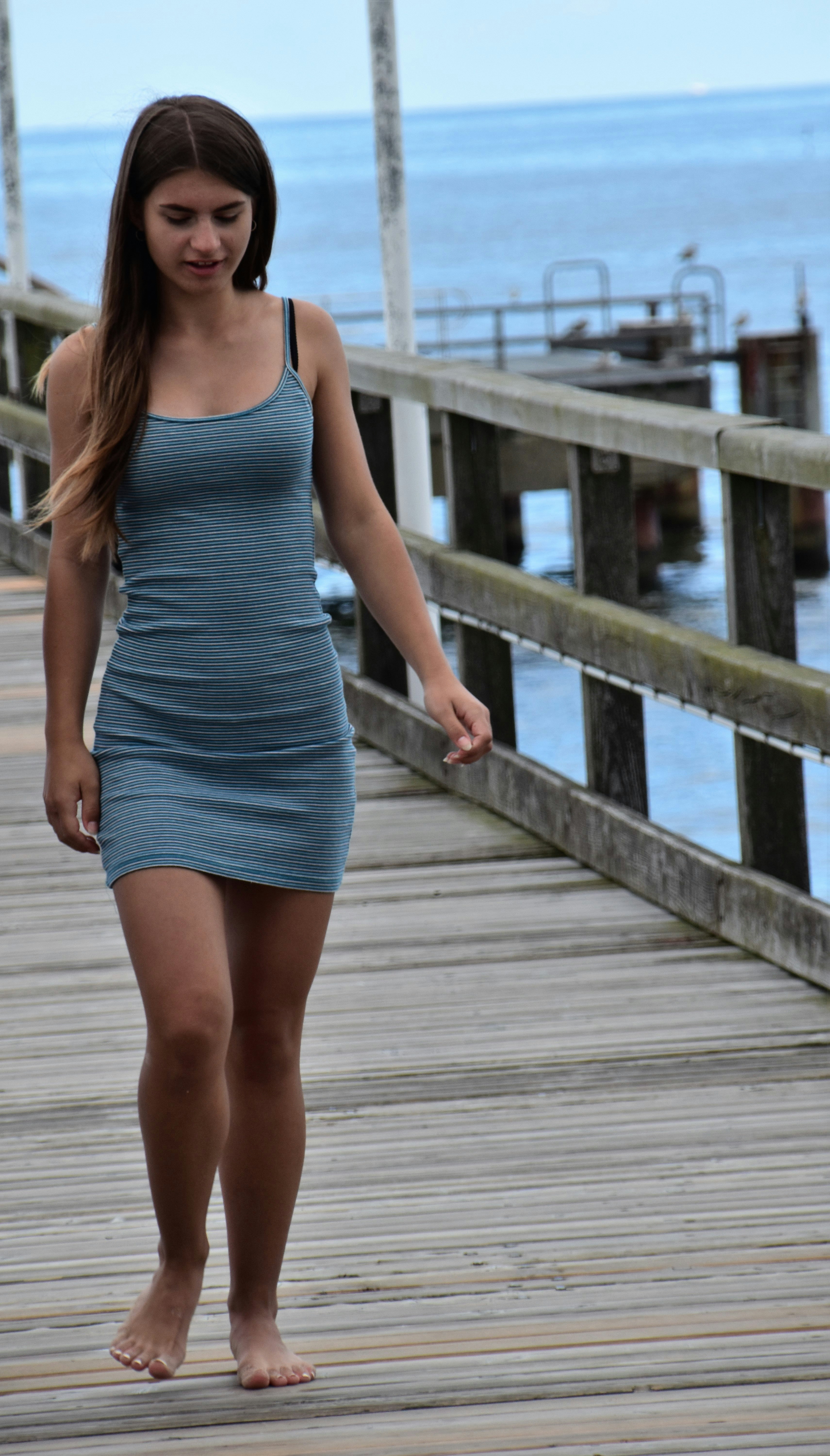 woman in blue spaghetti strap dress standing on wooden bridge